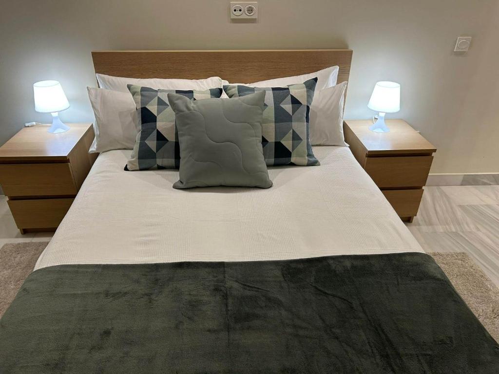 un grande letto con cuscini e due lampade sui tavoli di Apartamento Fibes-Congresos Parking Gratis a Siviglia