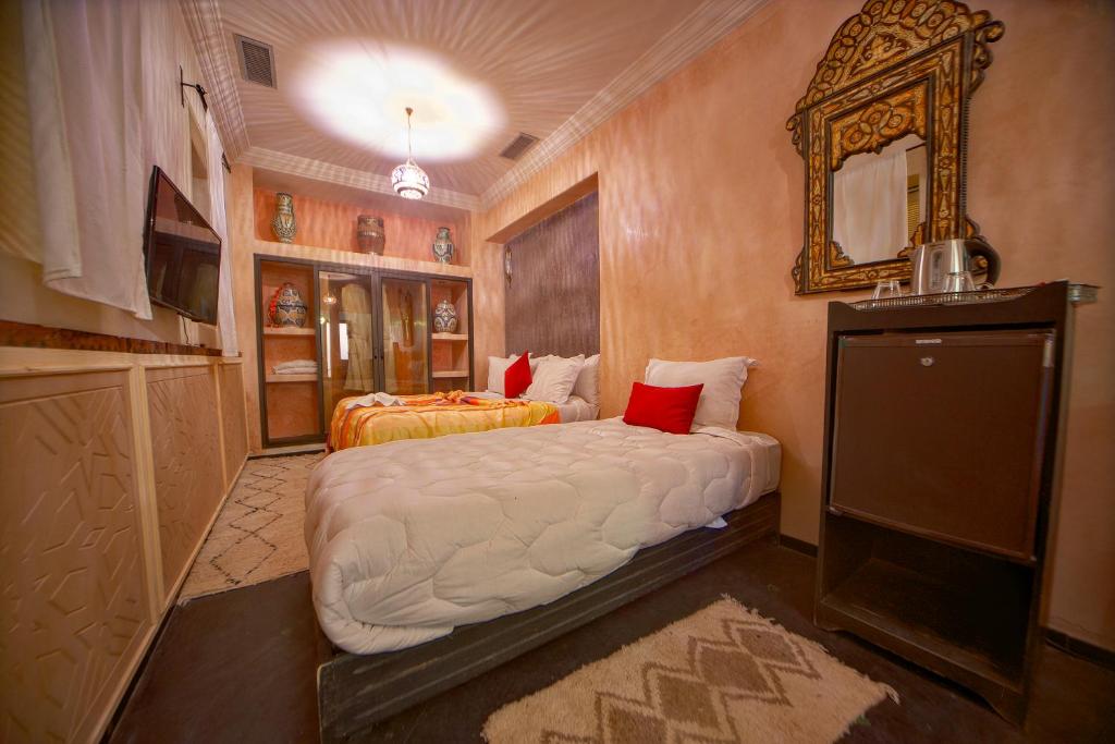 a bedroom with two beds and a mirror at Riad Tama & spa in Ouarzazate