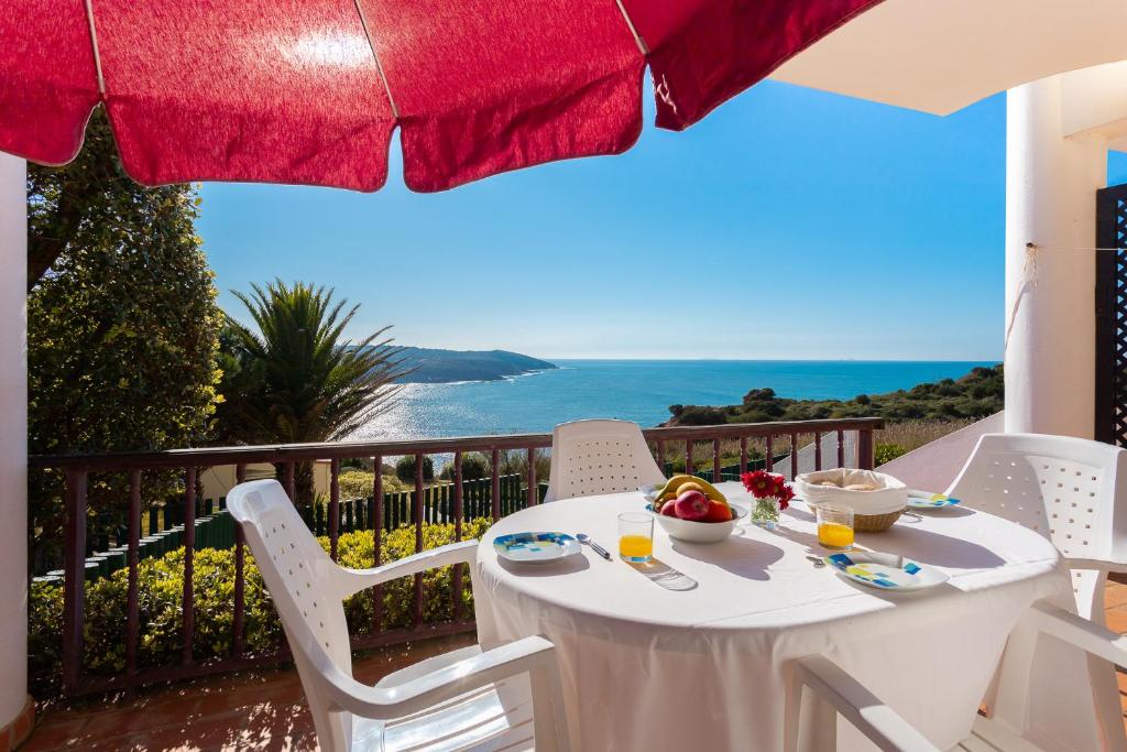 - une table et des chaises blanches sur un balcon donnant sur l'océan dans l'établissement Surf- Com vista para o Oceano, à São Martinho do Porto