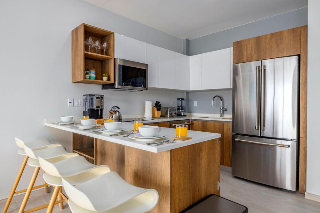 a kitchen with a counter with chairs and a refrigerator at HH-2Bdr510 - Luxury Oceanfront Modern apartment in Aruba in Oranjestad