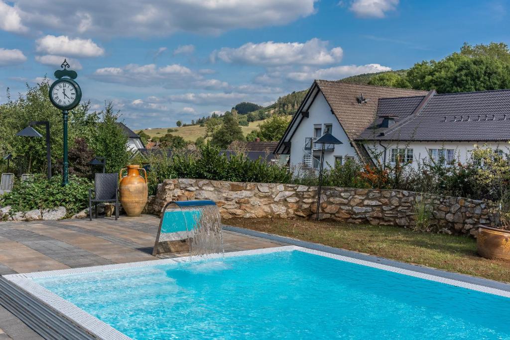 een zwembad met een klok naast een huis bij Struck Landhotel & SPA in Attendorn
