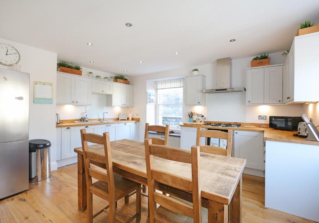 a kitchen with white cabinets and a wooden table and chairs at The Botanics Residence in Edinburgh