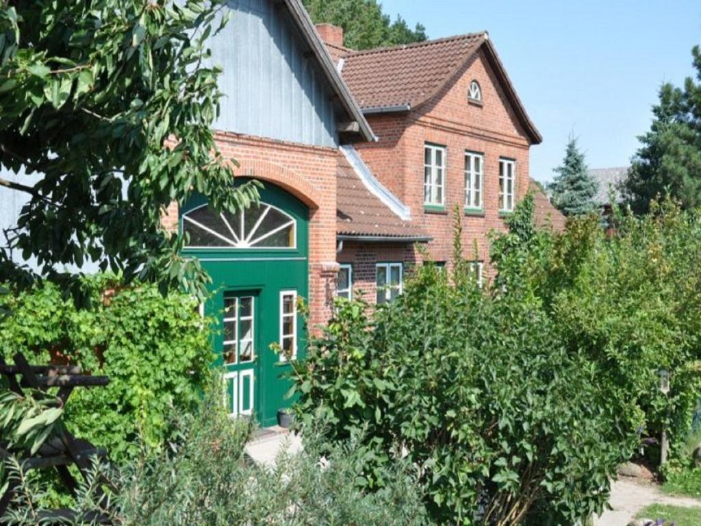 una casa con una puerta verde en un jardín en Hof Tummetott, en Mittelangeln
