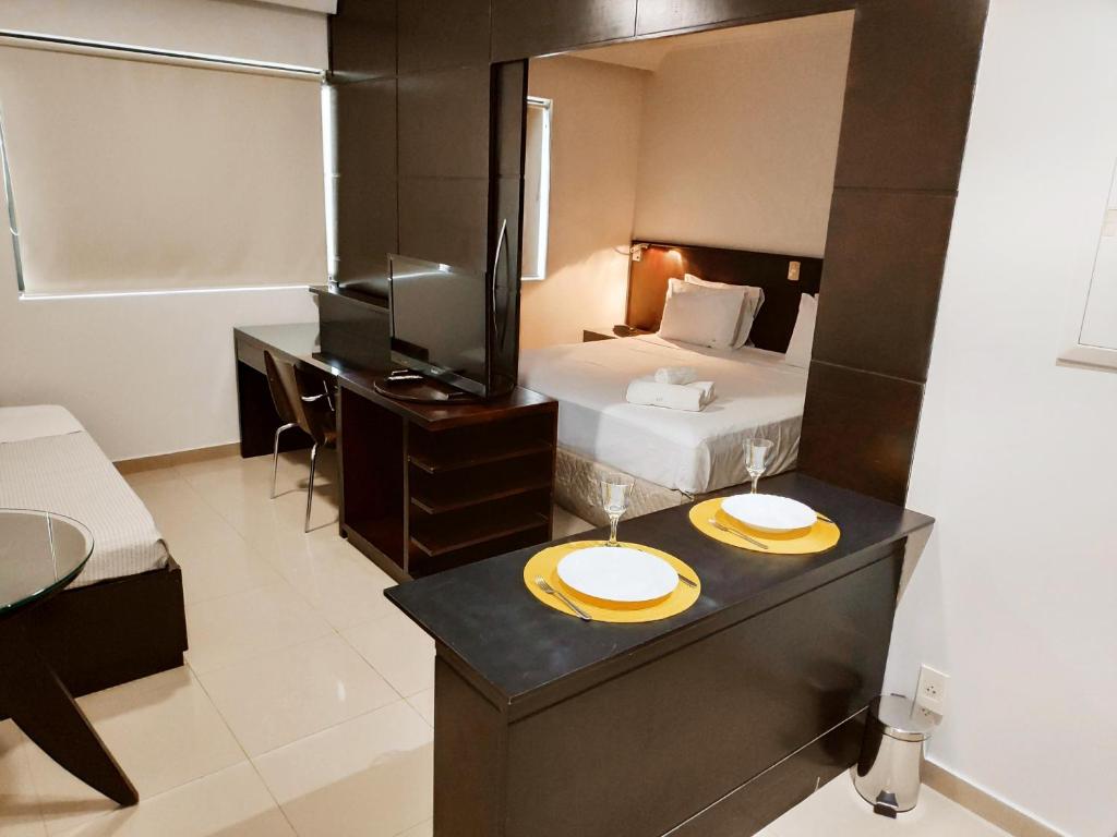 a hotel room with a bed and a table with two plates on it at Lindo Flat Luxuoso em Moema Ibirapuera - Apto 1320 in Sao Paulo