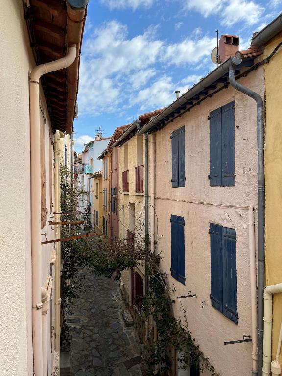Une allée entre deux bâtiments dotés de volets bleus. dans l'établissement 6CONV21 Maison de pêcheur au Faubourg, à Collioure