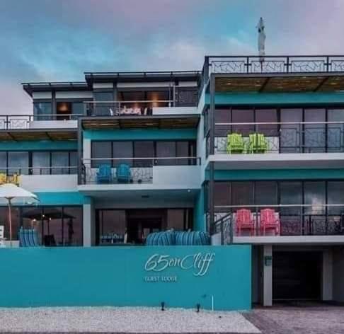 a blue building with chairs on the balcony at 65onCliff in Gansbaai