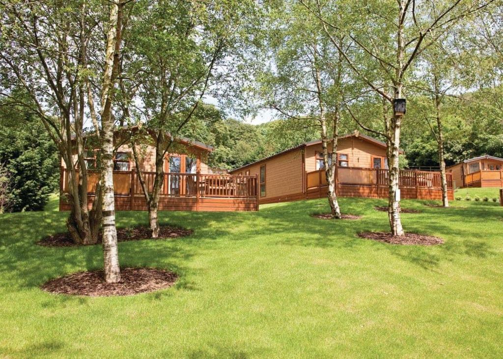a house with a yard with trees in front of it at Cheddar Woods Resort And Spa in Cheddar