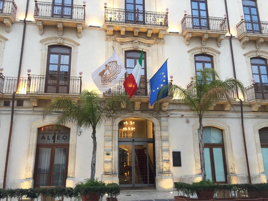 敘拉古的住宿－阿爾伯格阿爾費歐大酒店，前面有两面旗帜的建筑