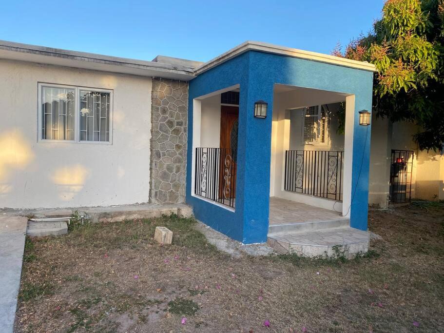 una casa con una puerta azul y un porche en Tranquil Oasis in Mona en Kingston