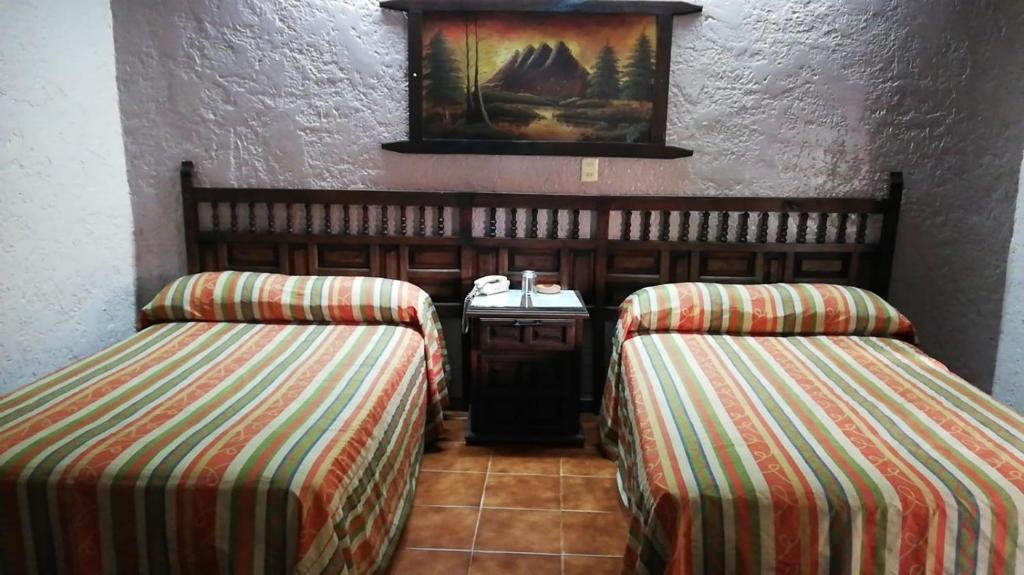 Habitación con 2 camas y una foto en la pared. en Hotel Iberia en Córdoba