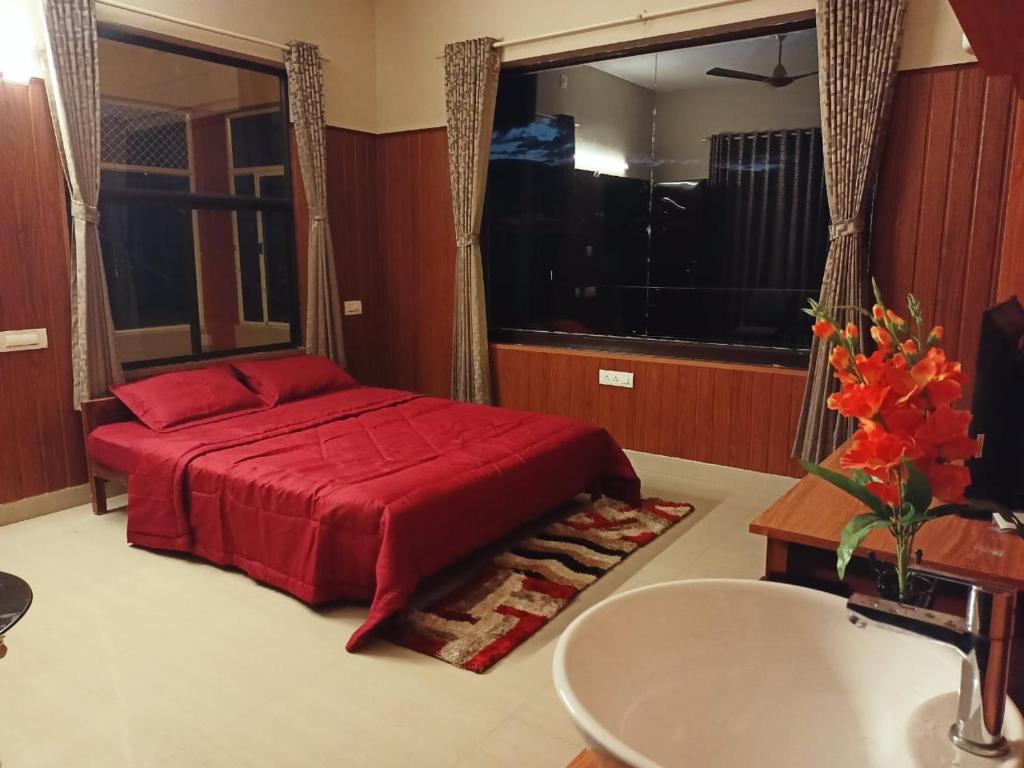 um quarto com uma cama vermelha e um lavatório em Alcyone Valley Panchalimedu em Pīrmed