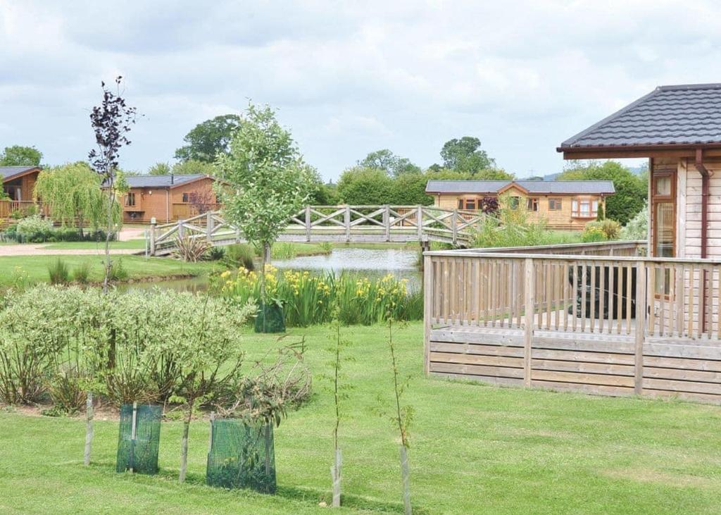 a garden with a wooden fence and a pond at York House Country Park in Thirsk