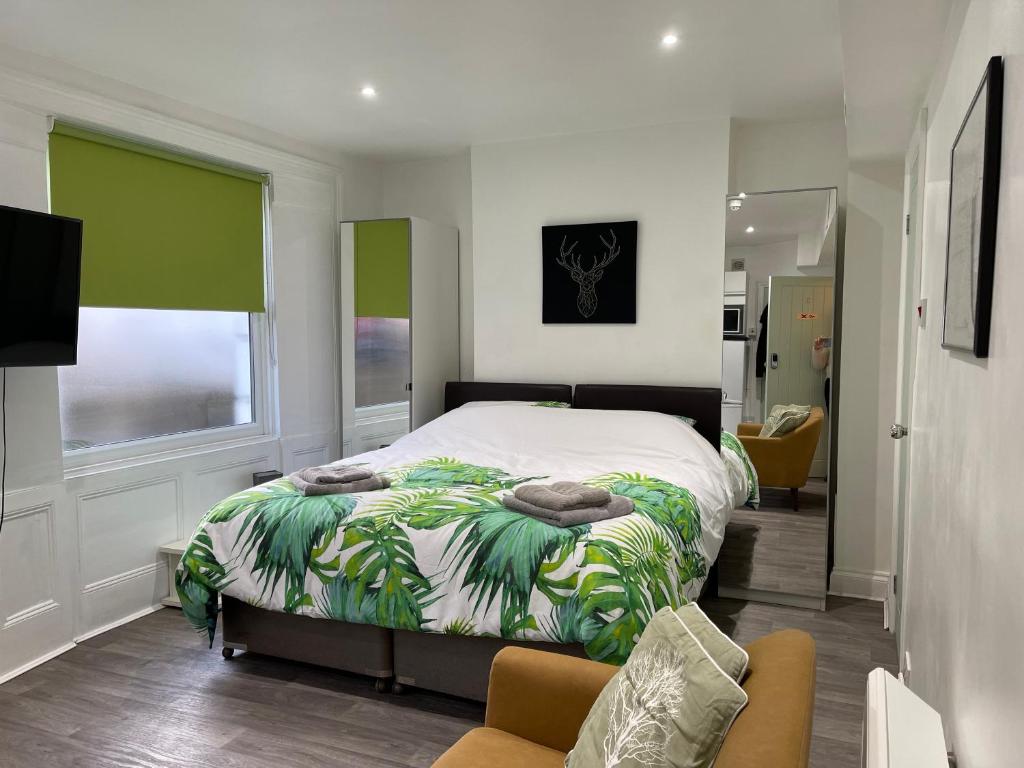 ein Schlafzimmer mit einem Bett mit einer grünen und weißen Decke in der Unterkunft Mildmay Road Apartments in London