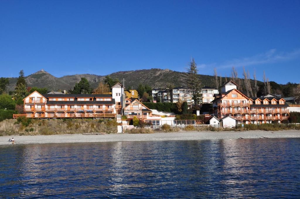 um grande edifício na costa de uma massa de água em Apart Del Lago em San Carlos de Bariloche
