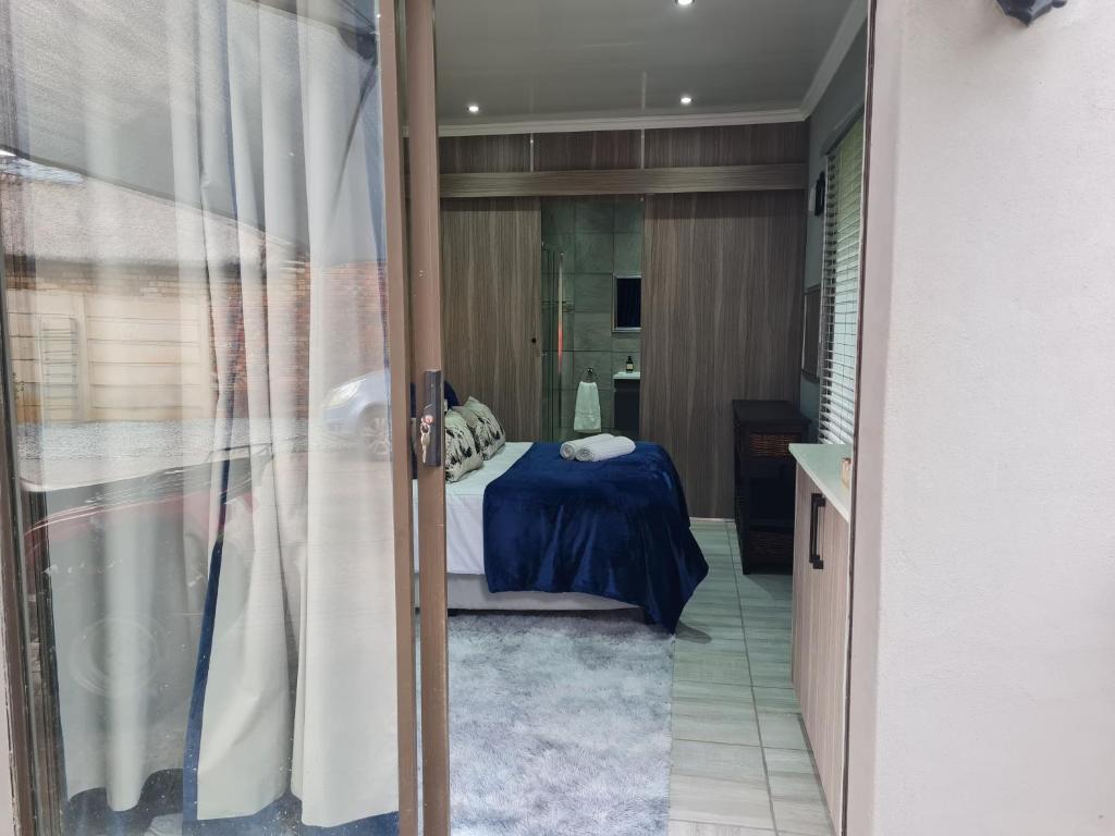een slaapkamer met een bed en een glazen deur naar een badkamer bij Rus 'n Bietjie in Bothaville