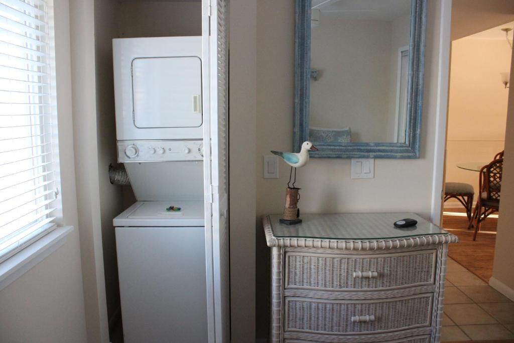 Cette chambre comprend un réfrigérateur blanc et un miroir. dans l'établissement Shipwatch # 304, à East End