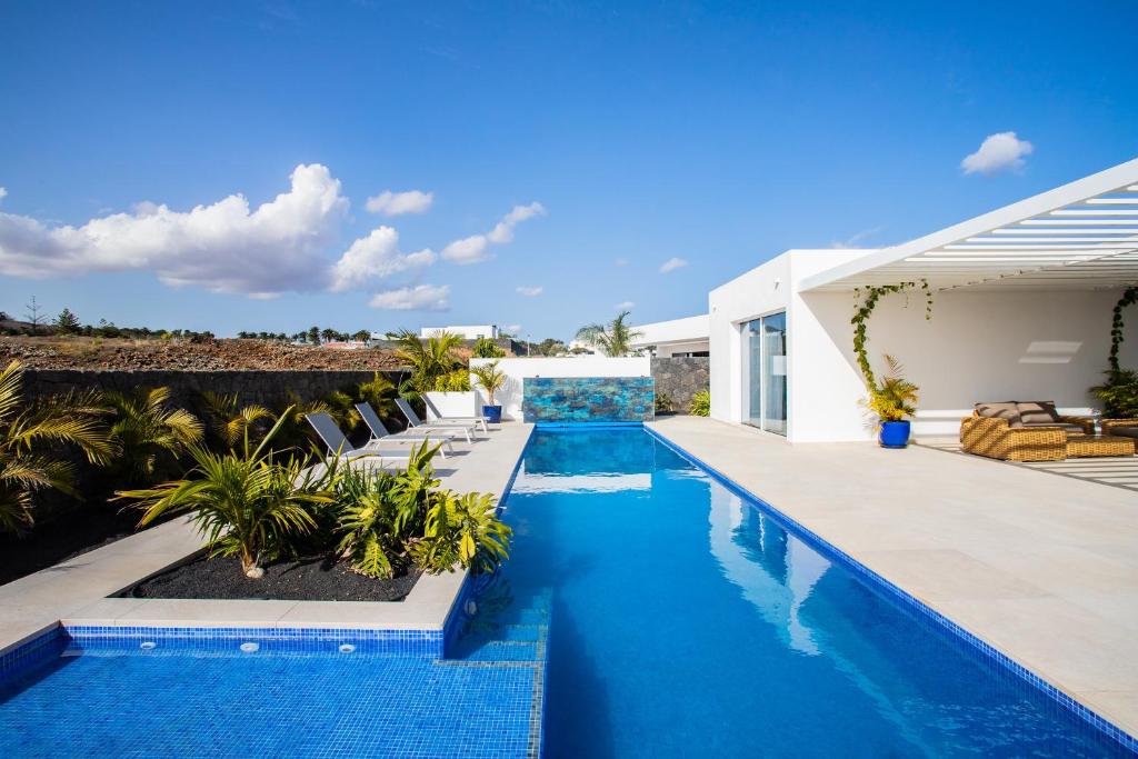 - une piscine d'eau bleue dans une maison dans l'établissement Golf Palms, à Costa Teguise