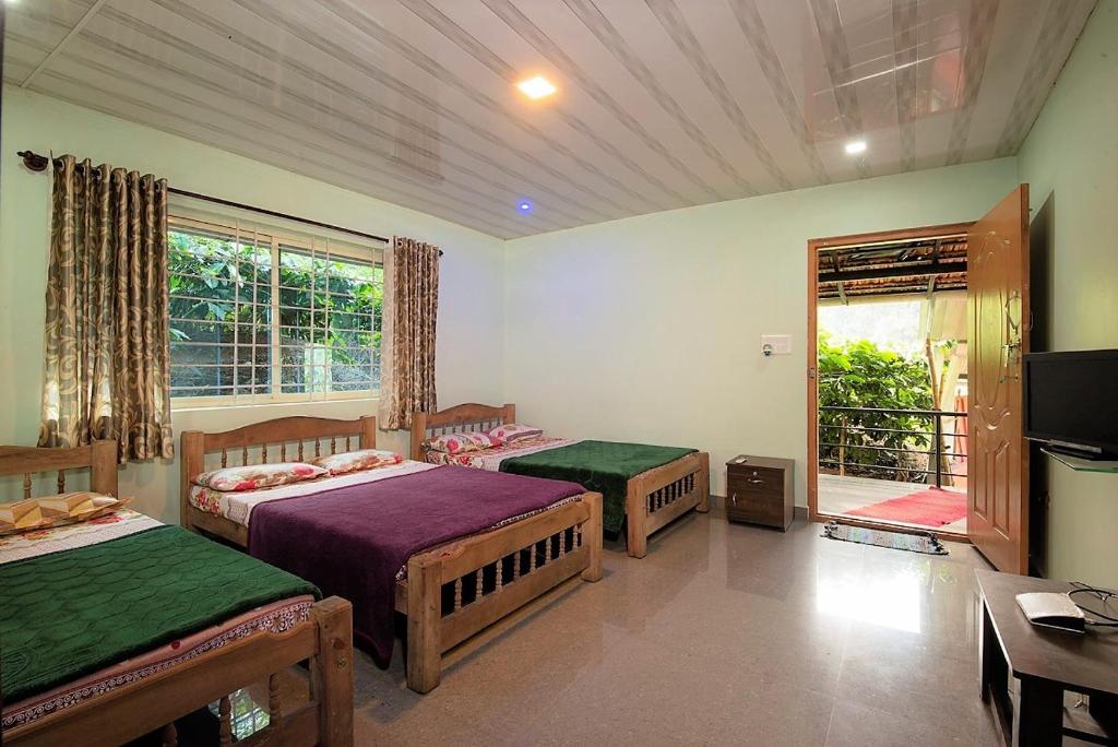 a bedroom with two beds and a television in it at Hiddenvalley Stays - Riverside in Madikeri