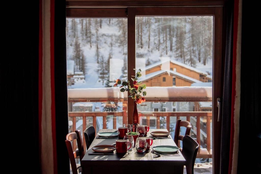 una mesa en un balcón con vistas a la nieve en Victoria Lodge, Friendly Hotel en Val dʼIsère
