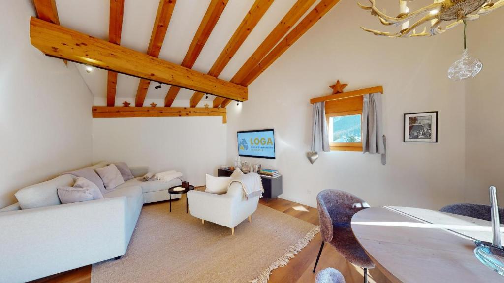 una sala de estar con muebles blancos y techos de madera. en Abitaziun Cravunera - Sils Maria, en Sils-Maria