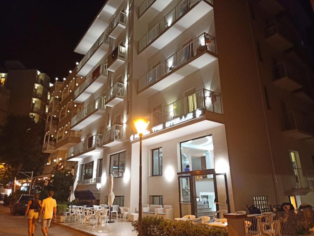 two people walking past a building at night at Hotel Tre Stelle Gabicce Mare in Gabicce Mare
