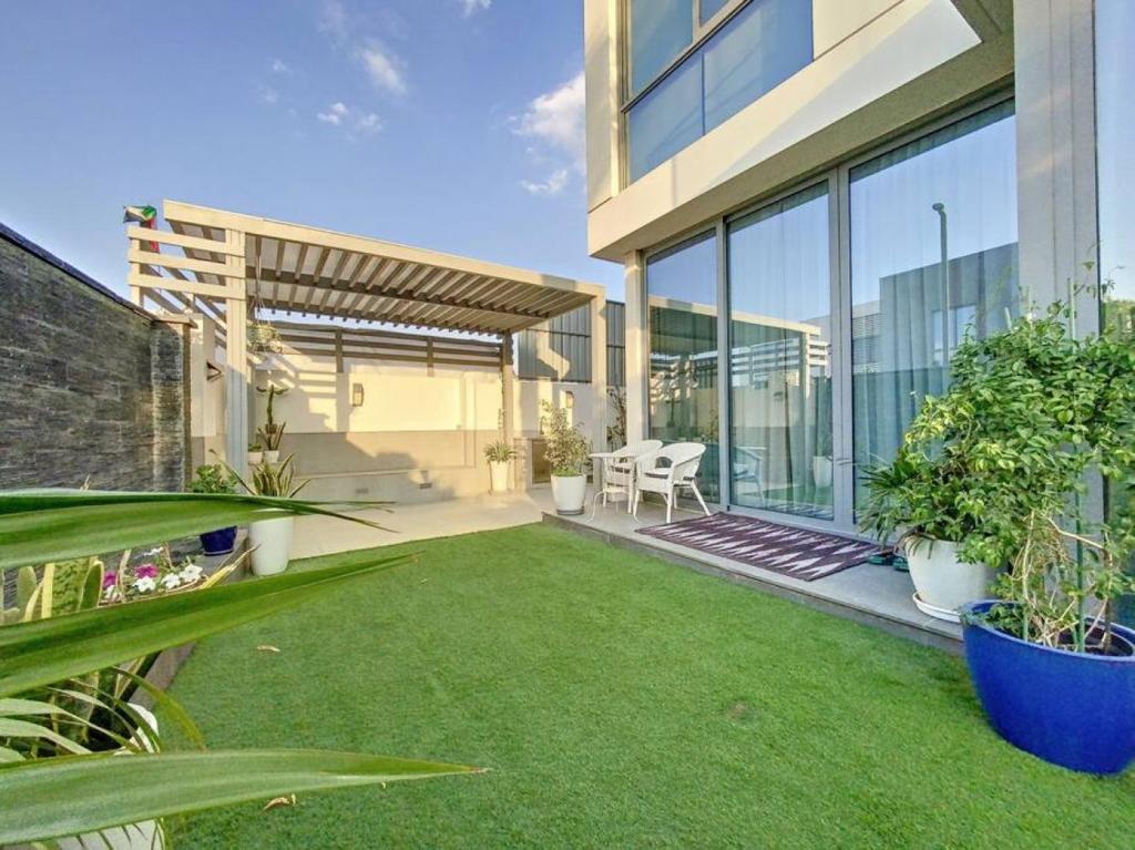a backyard with a lawn with plants and a building at Key View - Villa Gardenia Jebel Ali in Dubai
