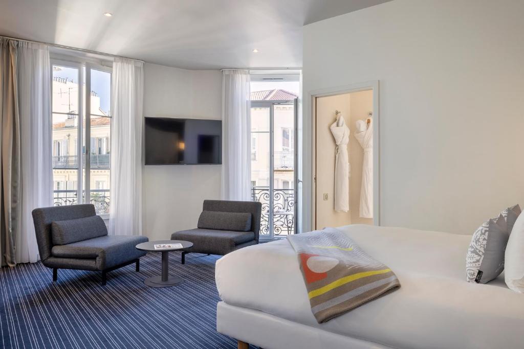 فندق 66 نيس في نيس: غرفة معيشة مع أريكة بيضاء وكرسي