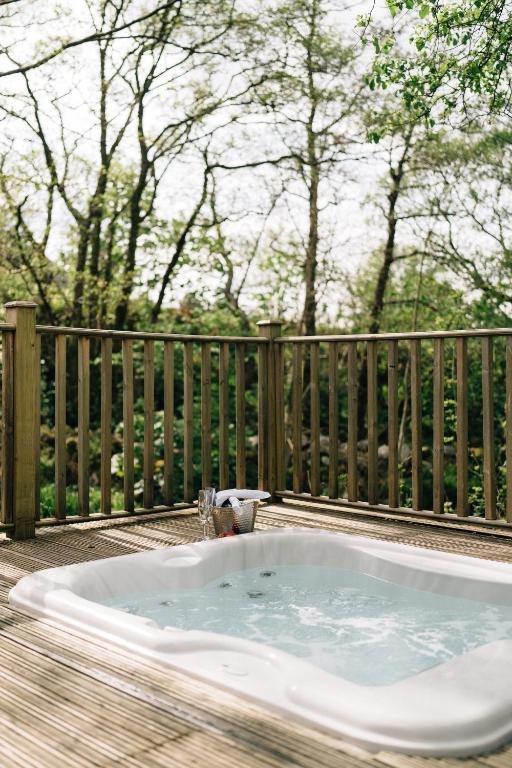 a hot tub on a deck with a fence at RiverBeds - Luxury Wee Lodges with Hot Tubs in Glencoe