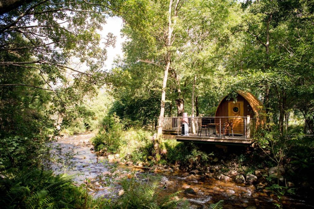 a woman sitting on a bridge in a tree house at RiverBeds - Luxury Wee Lodges with Hot Tubs in Glencoe
