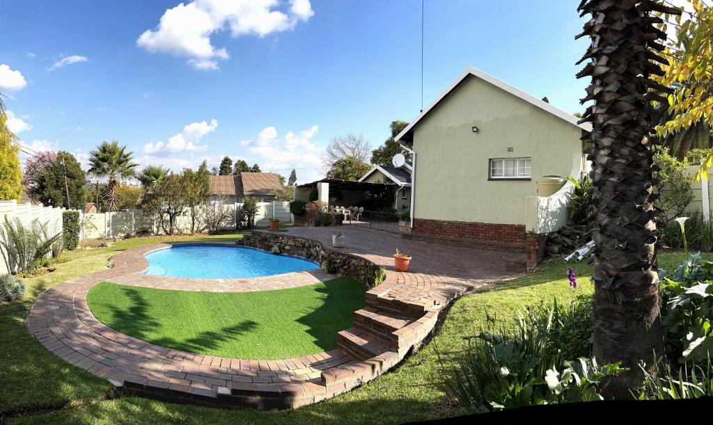 a backyard with a swimming pool and a house at The Valley, tranquil 3 bedroom home with pool in Midrand