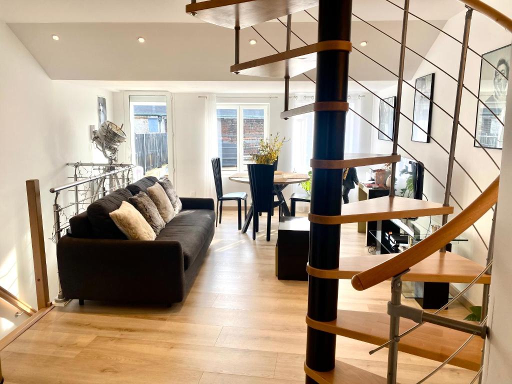 a living room with a couch and a spiral staircase at Appartement Léonard, comme à la maison - Vieux Lille in Lille