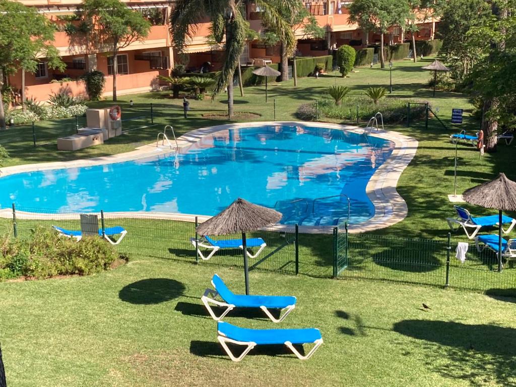 una piscina con sillas y sombrillas en un patio en Elviria Marbella Pinogolf en Marbella