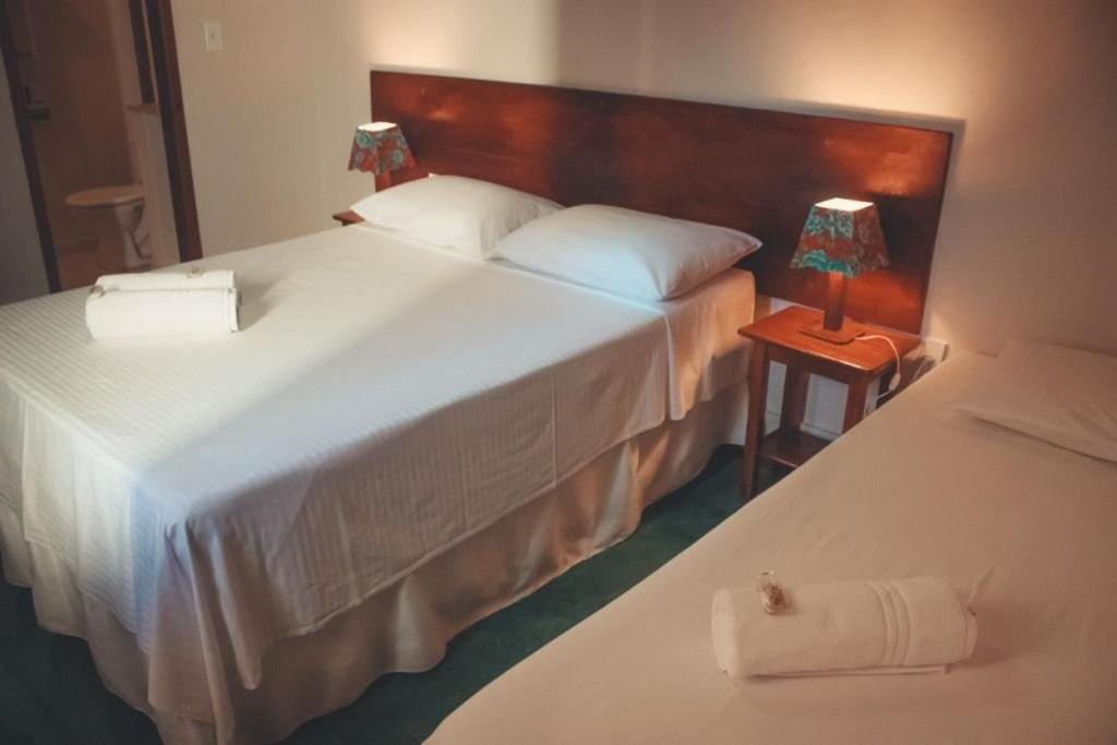 a hotel room with two beds and a table with a lamp at Pousada Hannah in Prado