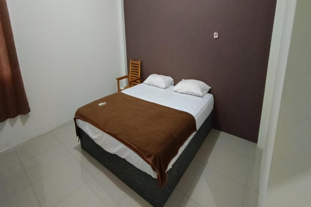 - une chambre dotée d'un lit avec un mur brun dans l'établissement OYO 92243 Fanilly Guest House Marabahan, à Banjarmasin