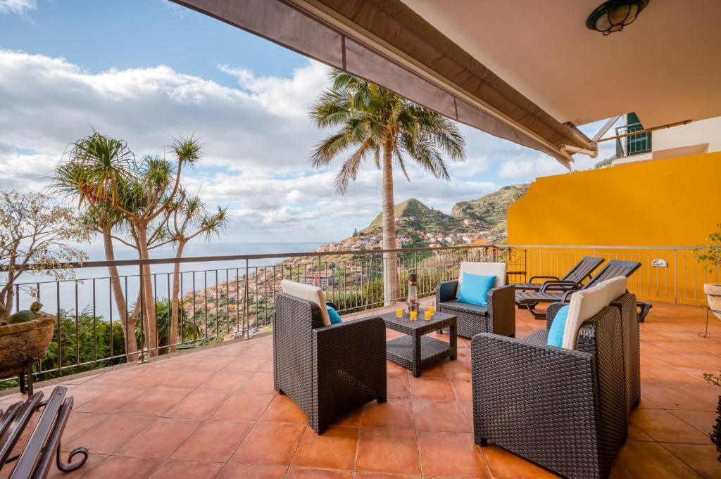 a patio with chairs and a view of the ocean at Palm Tree House in Câmara de Lobos