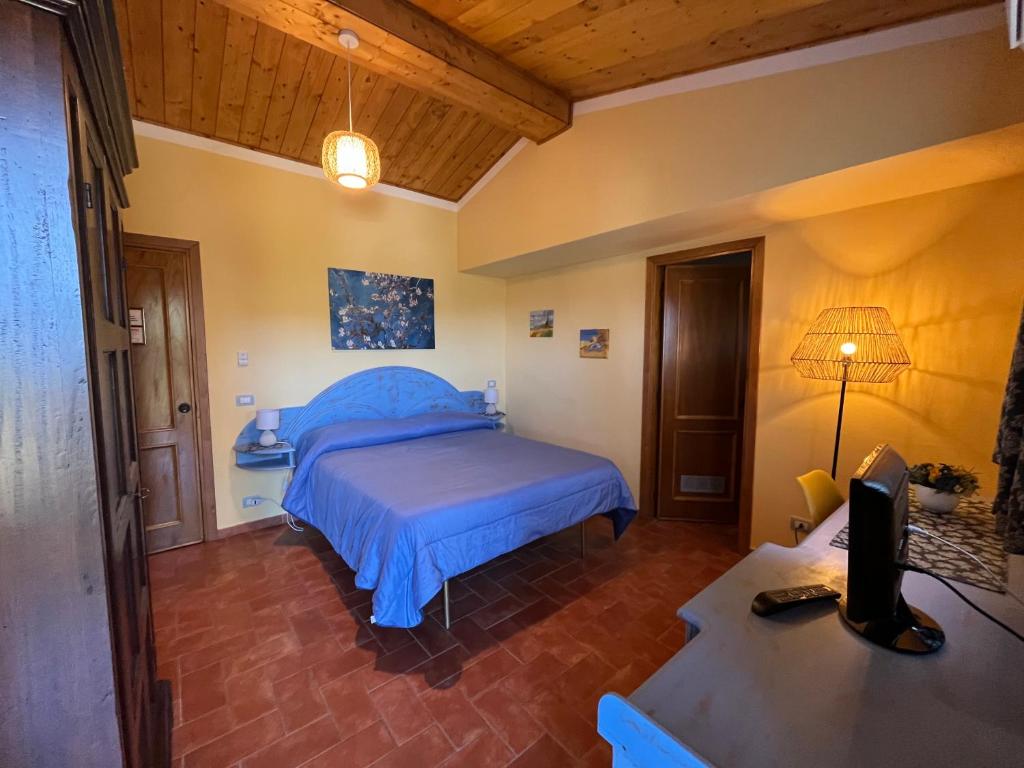 Schlafzimmer mit einem Bett und einem Schreibtisch mit einem TV in der Unterkunft Agriturismo Poggio del Drago in Montemerano