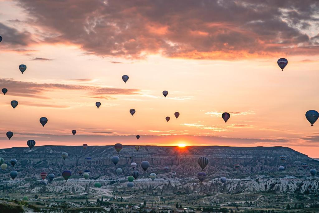 a group of hot air balloons in the sky at sunset at Maron Stone House in Goreme