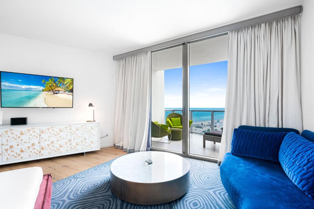 uma sala de estar com um sofá azul e uma grande janela em Ocean View Residence at W South Beach -1226 em Miami Beach