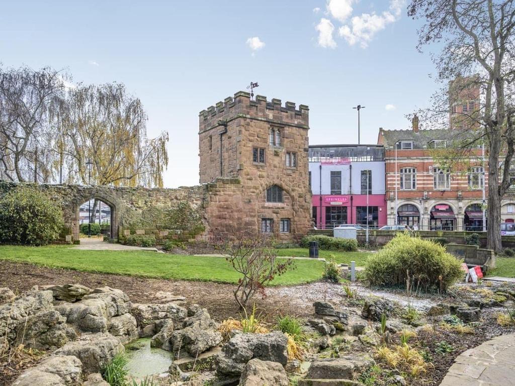 un antiguo edificio de piedra con un jardín delante de él en Swanswell Gate en Coventry
