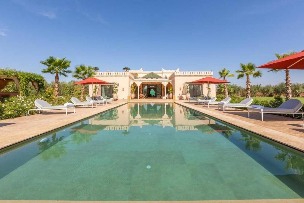 uma piscina com cadeiras e uma casa em Magnifique Villa Namaste louée avec le personnel de maison em Marrakech