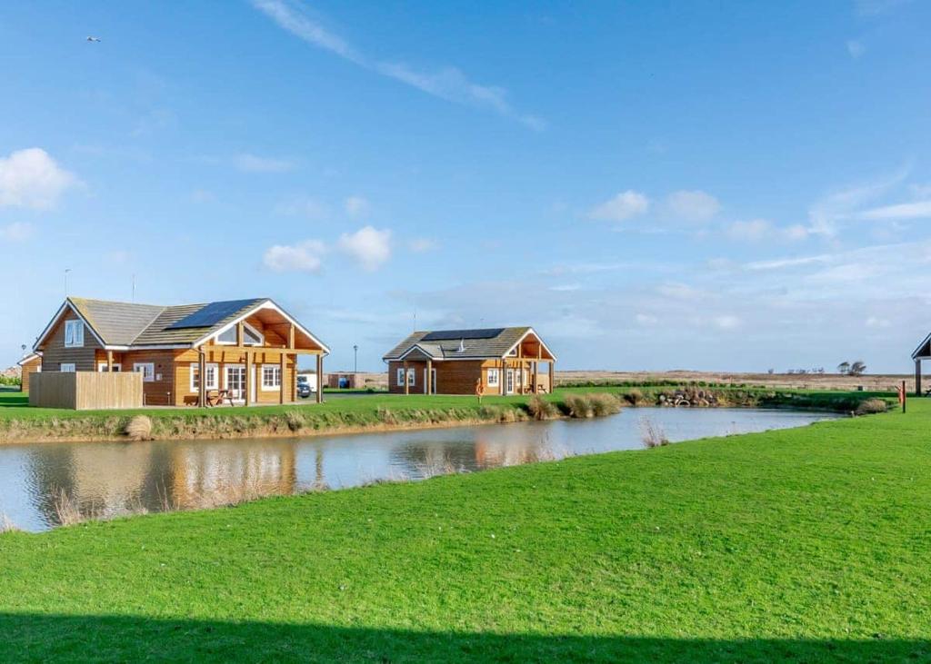 a row of houses in a field next to a river at Hornsea Lakeside Lodges in Hornsea
