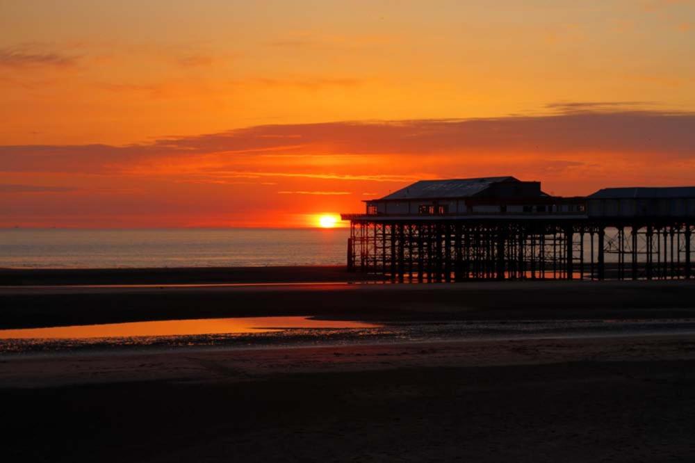 ブラックプールにあるRossall House , For Families & Couplesの夕日を背景に海岸の桟橋