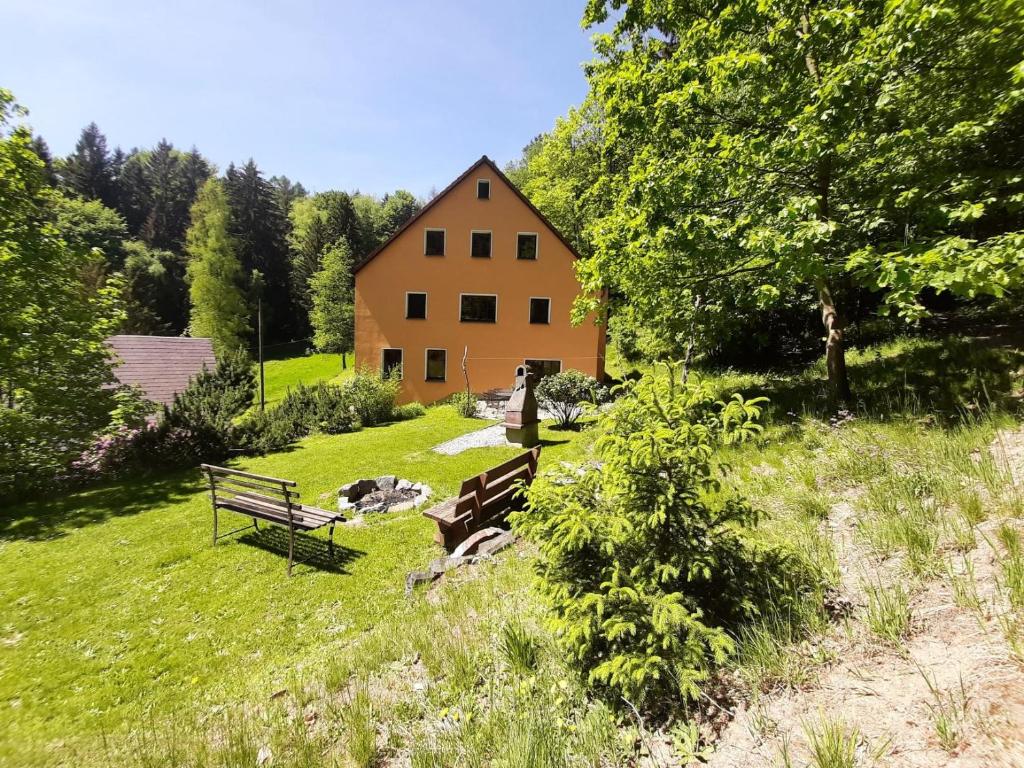 a bench in a field with a house in the background at Ferienwohnung Haus Sonnenblick in Luftkurort Lückendorf