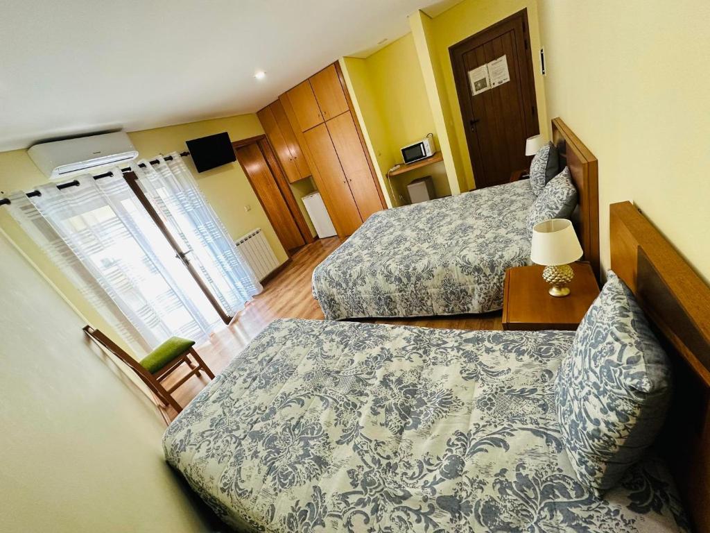 a hotel room with two beds and a chair at Residência Iris in Geres