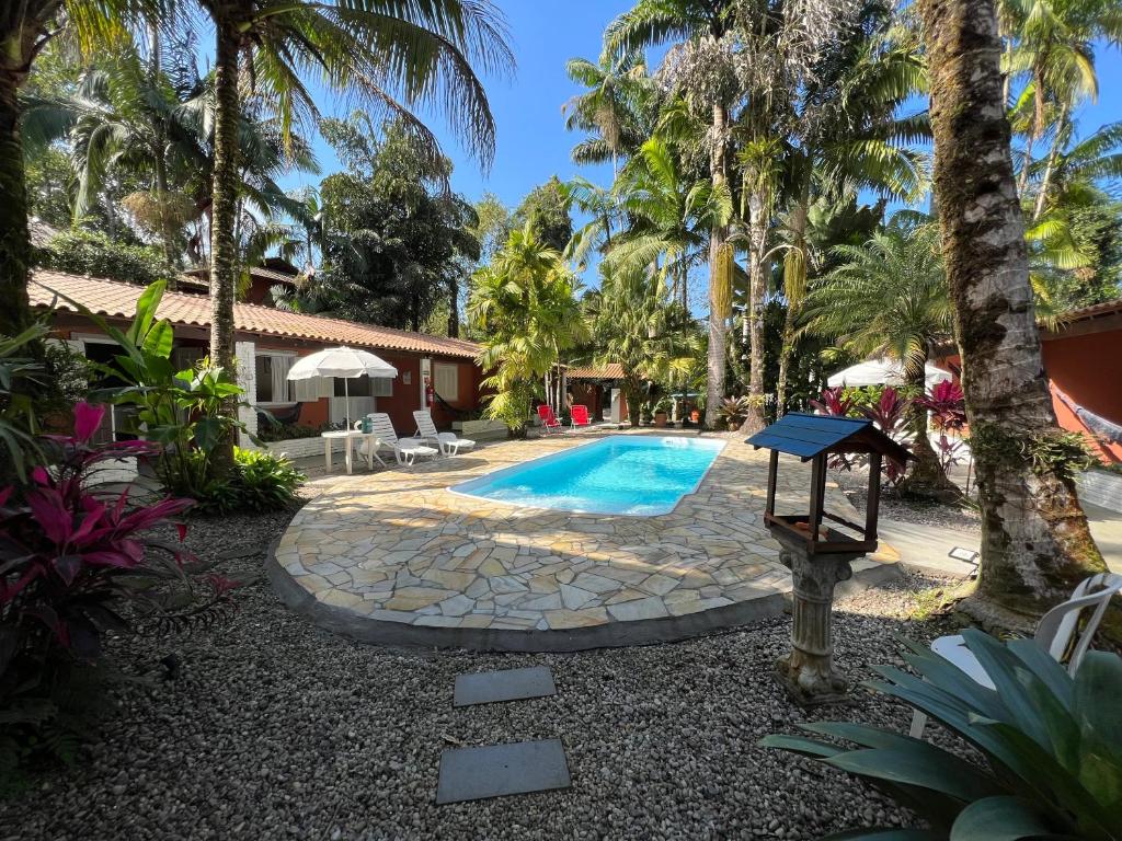 a backyard with a swimming pool and palm trees at Pousada Nova Ascalom in Ubatuba