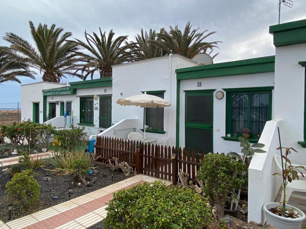Biały dom z parasolem i palmami w obiekcie CASA SANDRA COCOSOL w mieście Costa de Antigua