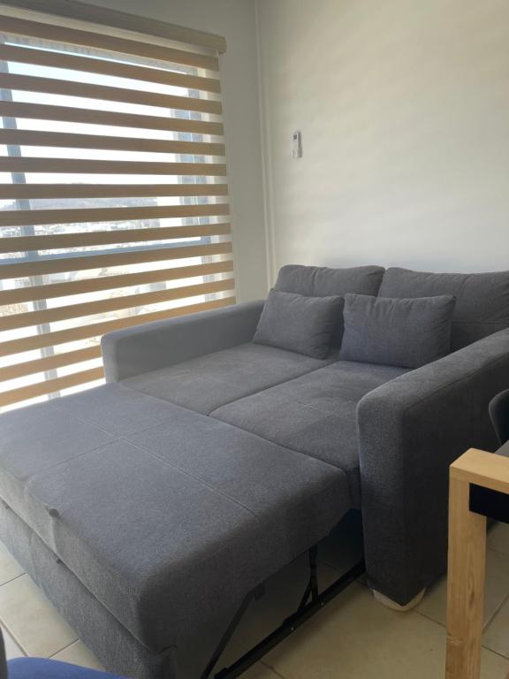 a gray couch in a living room with a window at Nuevo departamento a solo 3 min de la playa con todos los servicios in La Florida
