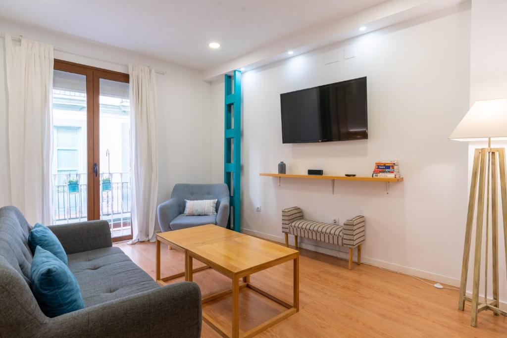 a living room with a couch and a table and a tv at Locksmith Apartment -Wifi- Park Option in Seville