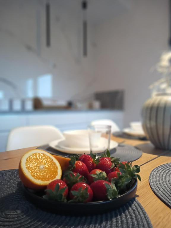 a plate of strawberries and an orange on a table at Apartament SEVENTH HEAVEN in Uniejow