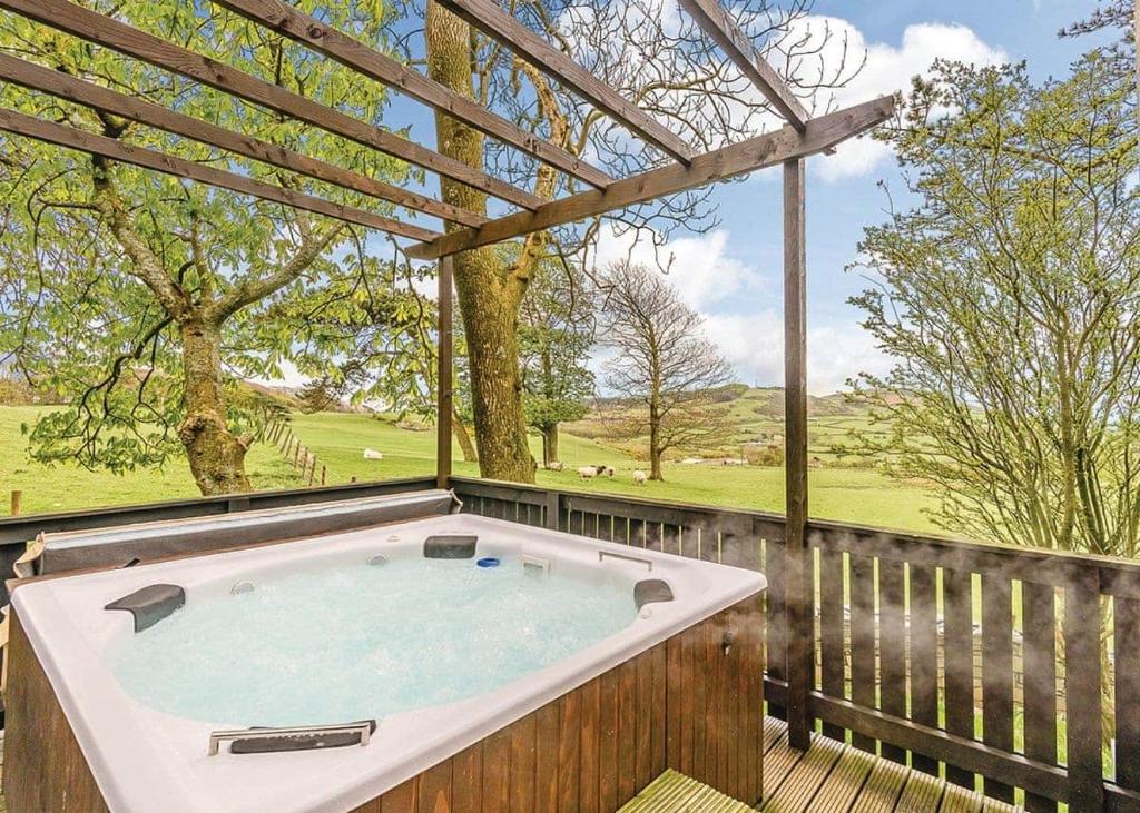 a hot tub on a wooden deck with a large window at Brockwood Hall Lodges in Silecroft